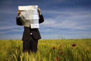 A person in a business suit in a field with a map