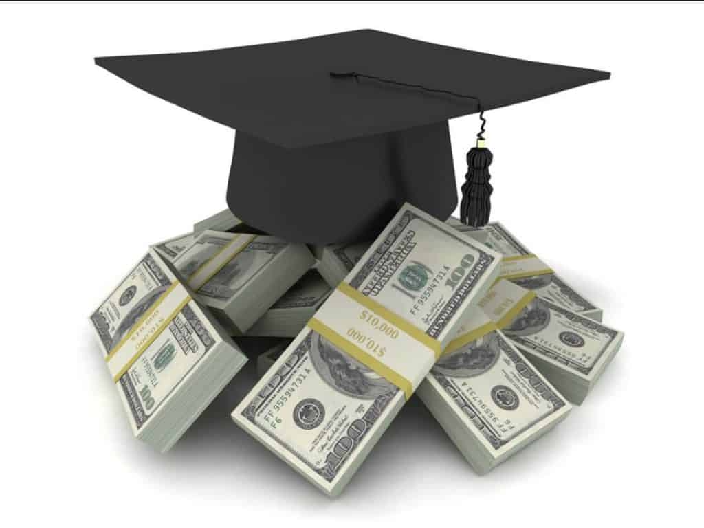 A graduation cap perched atop stacks of $100 dollar bills